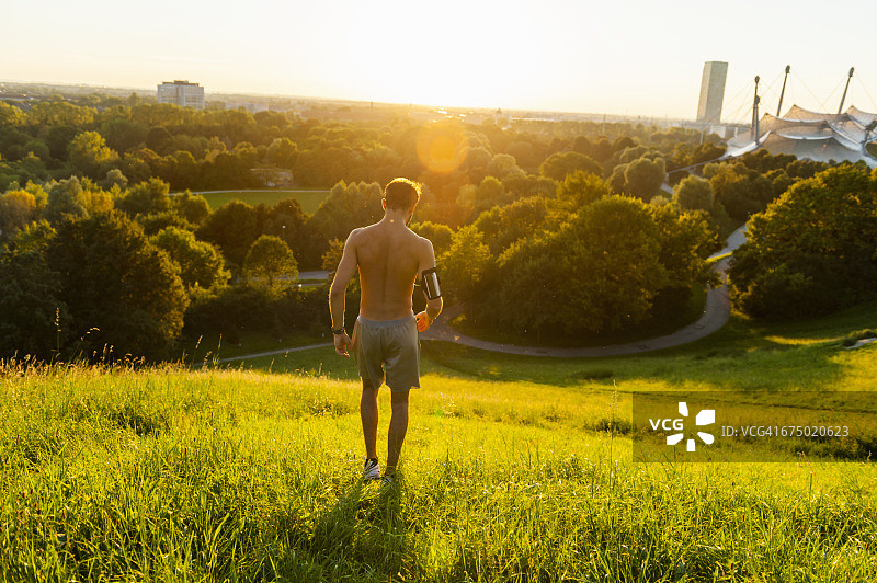 日落时分，赤裸上身的运动员在公园的草地上图片素材