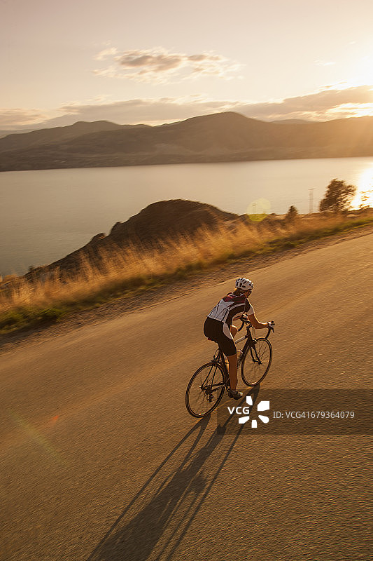 日落时分，骑自行车的人在风景优美的海滩路上骑行图片素材