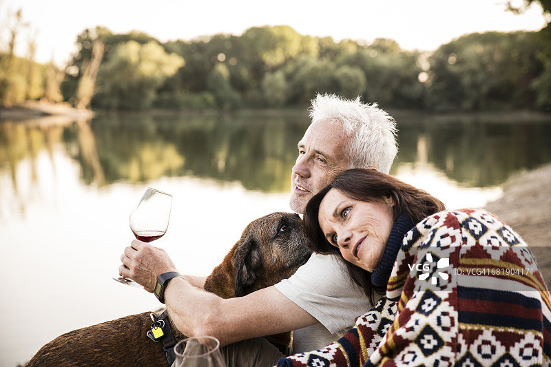 放松的老夫妇与狗和酒在湖边图片素材