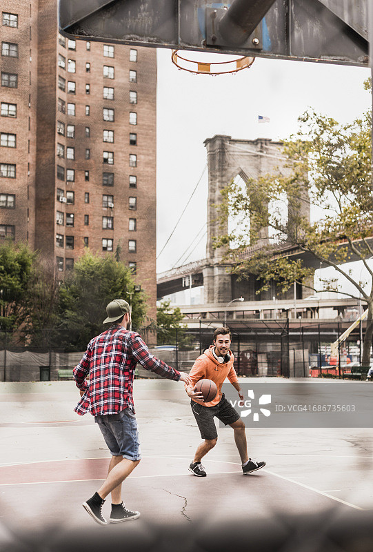 美国，纽约，两个年轻人在户外打篮球图片素材