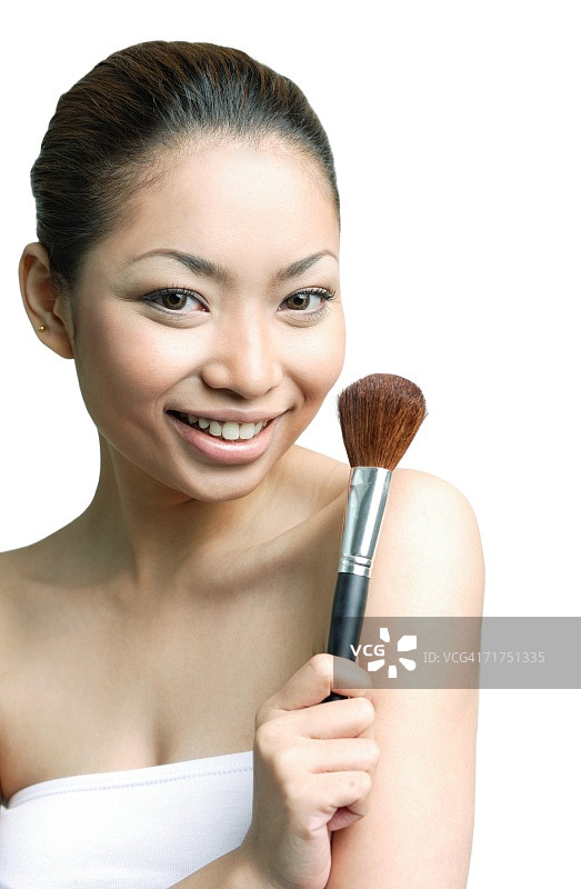 女人拿着化妆刷，对着镜头微笑图片素材