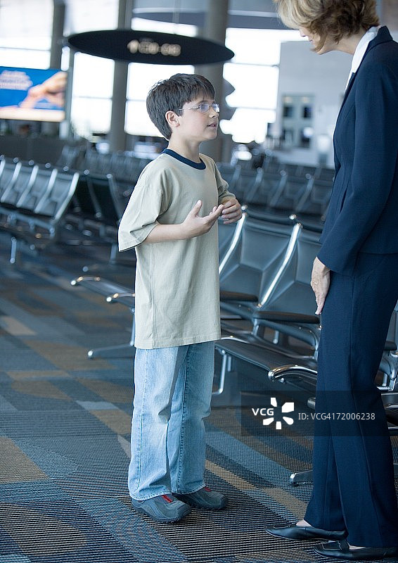 一个男孩在机场休息室和空乘人员说话图片素材