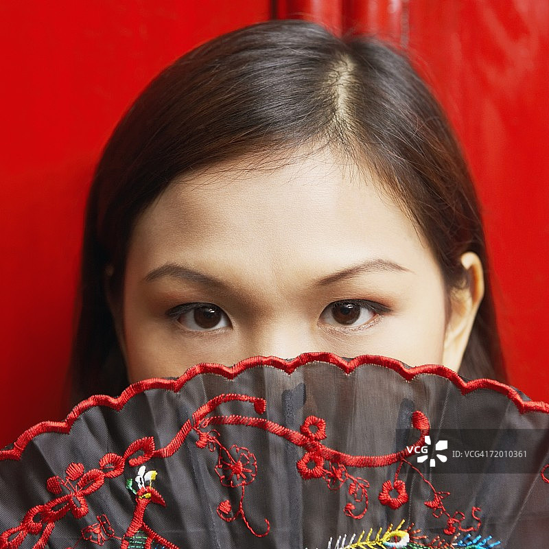 一个年轻女子的肖像用折扇遮住她的嘴图片素材