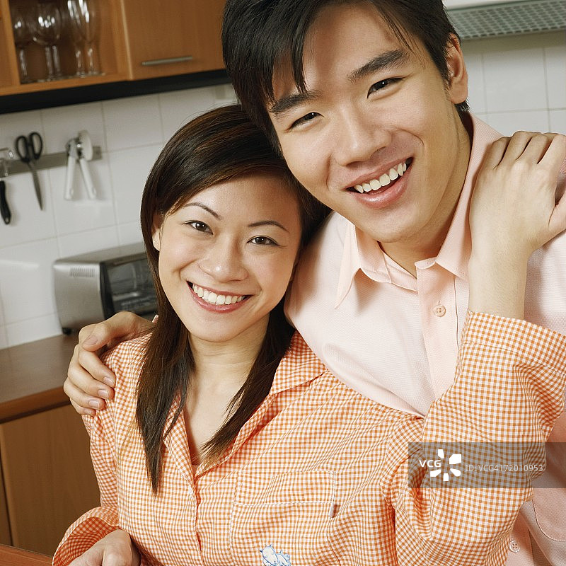 一对年轻夫妇在厨房柜台前微笑的肖像图片素材