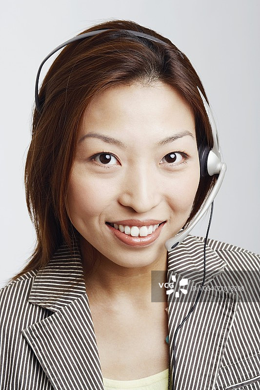 一个戴着耳机微笑的女商人的肖像图片素材