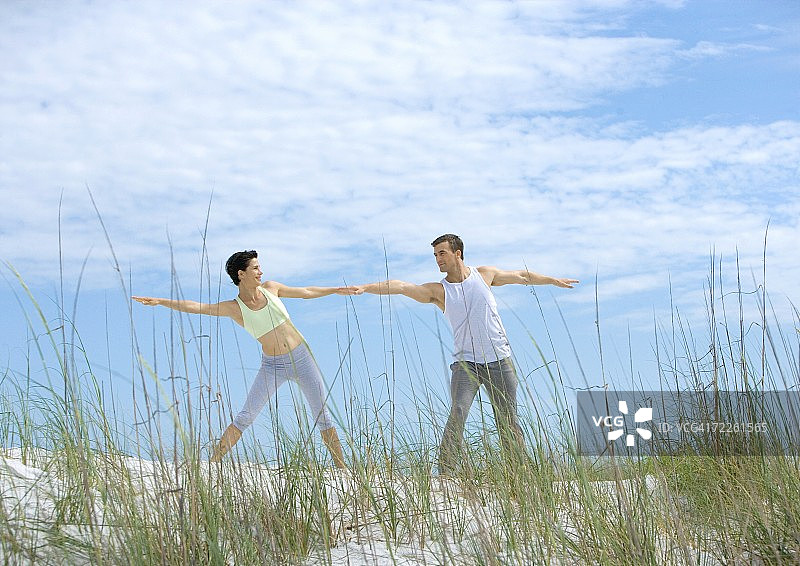 男人和女人在沙滩上做伸展运动图片素材