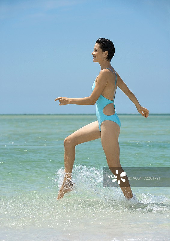 女人在冲浪，侧视图图片素材