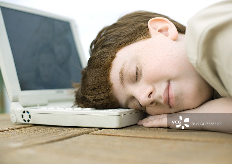 男孩枕着电脑睡觉图片素材