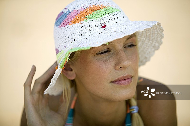年轻女子在海滩上，戴着帽子，画像图片素材