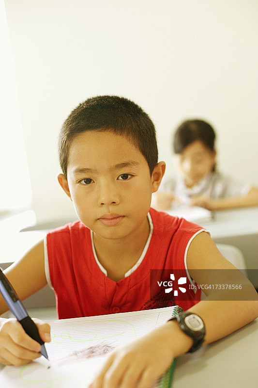 一个男孩的肖像写在螺旋笔记本在教室里图片素材