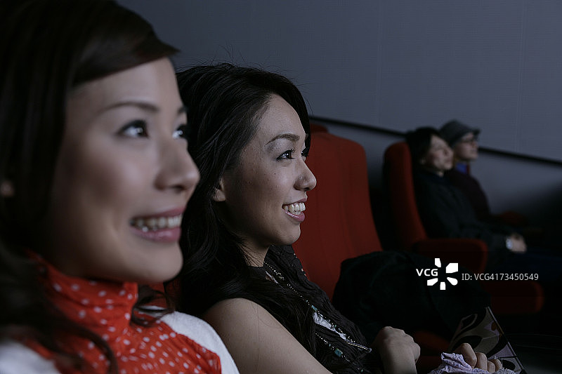 两个年轻女人在电影院看电影的特写图片素材