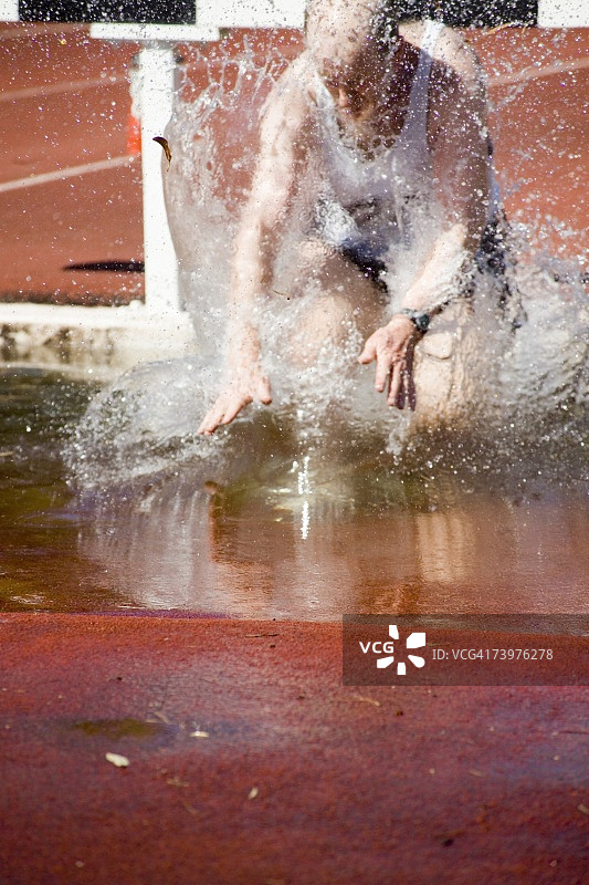 在障碍赛跑项目中，男子跌落水中图片素材