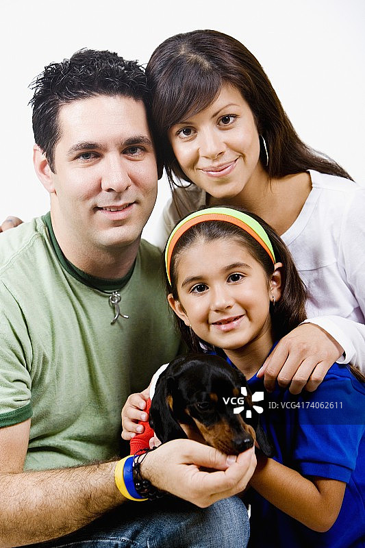 一个女孩和她的父母抱着一只小狗的肖像图片素材