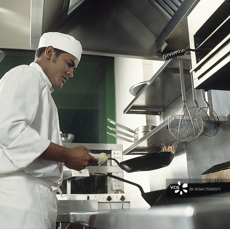 厨师在餐厅厨房炒菜，侧视图图片素材