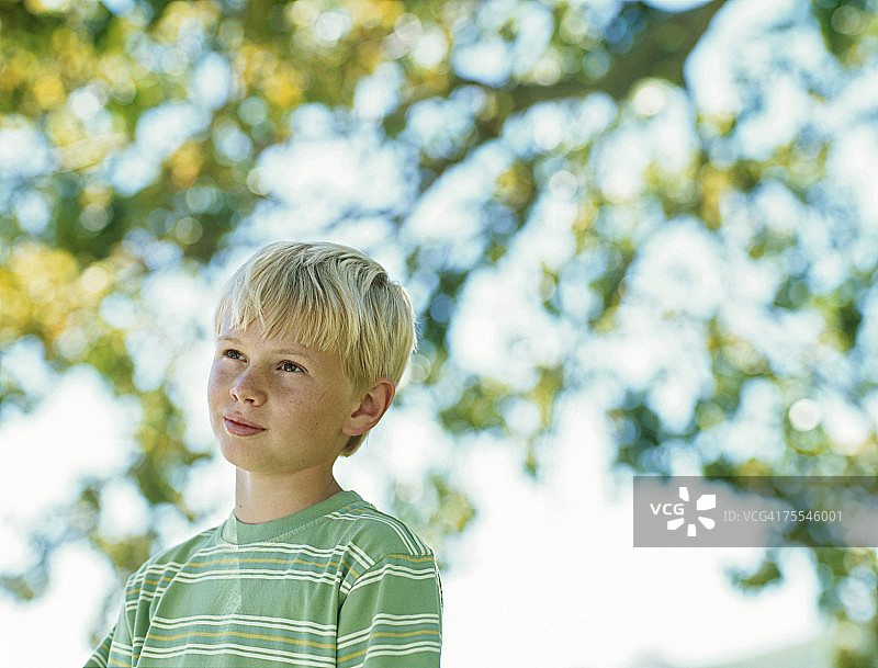 男孩(11-12)在户外，看着别处，微笑着图片素材