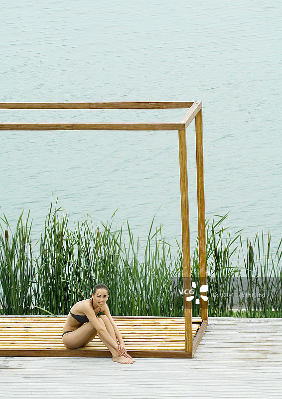 女人坐在方形结构，水体在背景图片素材