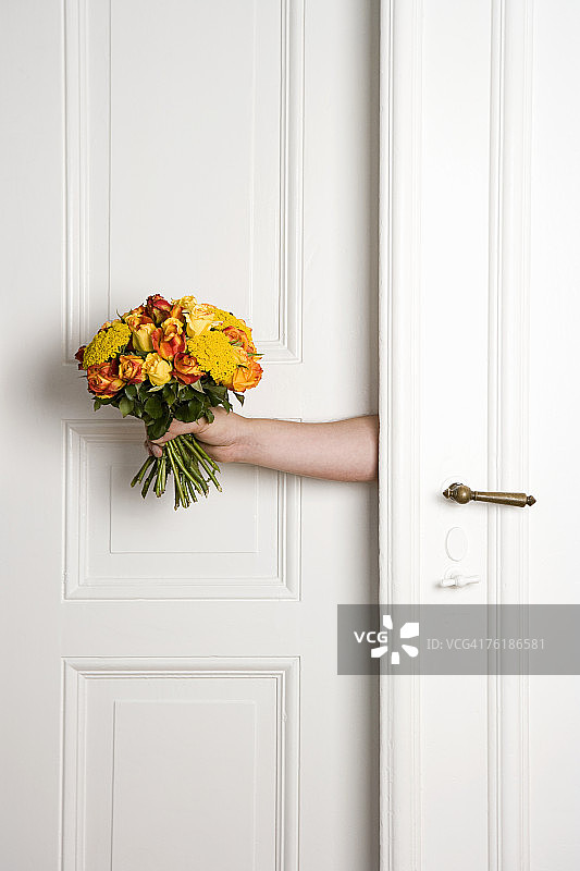 一个男人拿着一束花在门里图片素材