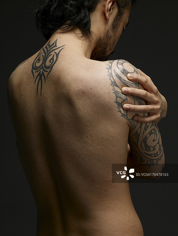 一个有纹身的裸胸男人的背部图片素材