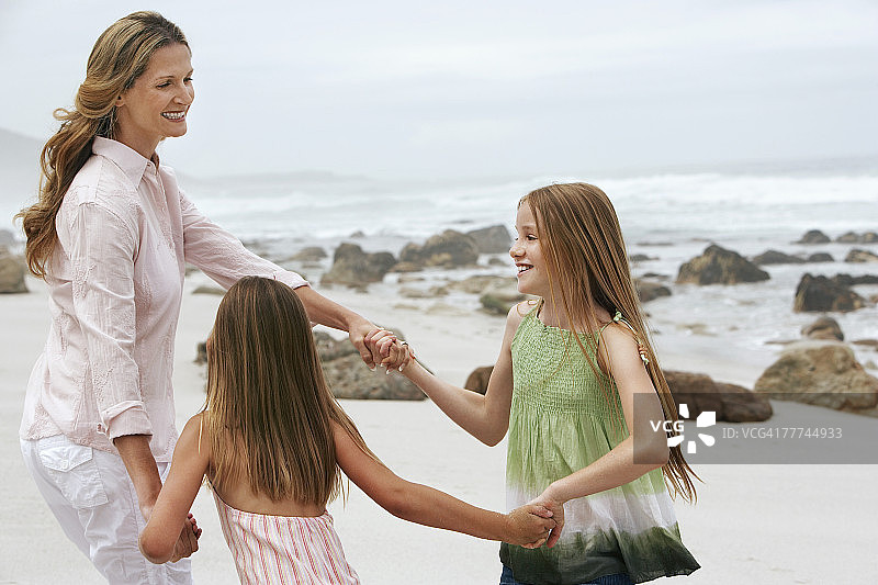 母亲和两个女孩在海滩上玩耍图片素材