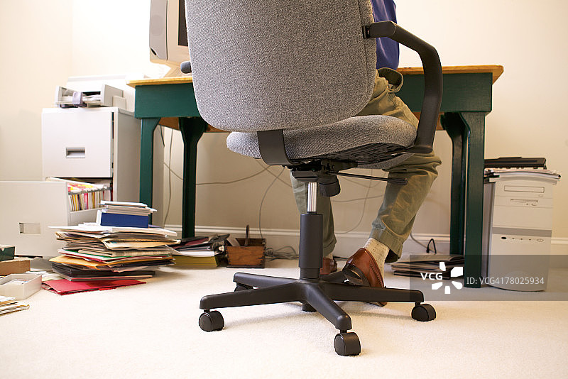 一个男人在家里工作的桌子上的椅子的近距离后视图图片素材