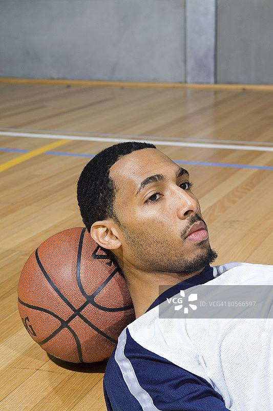 一个年轻人把头靠在篮球上图片素材