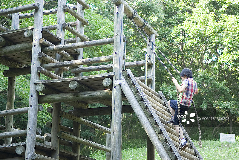 在公园里爬木结构的男孩图片素材