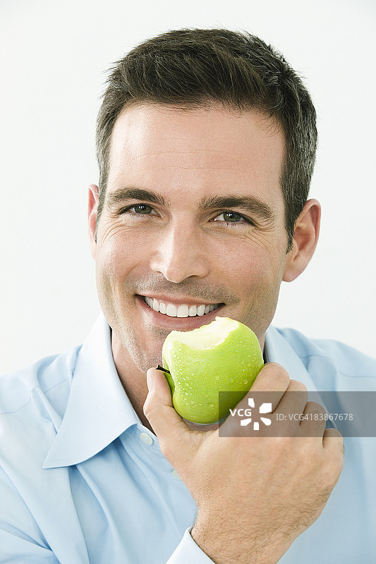 一个人拿着苹果微笑着，特写图片素材