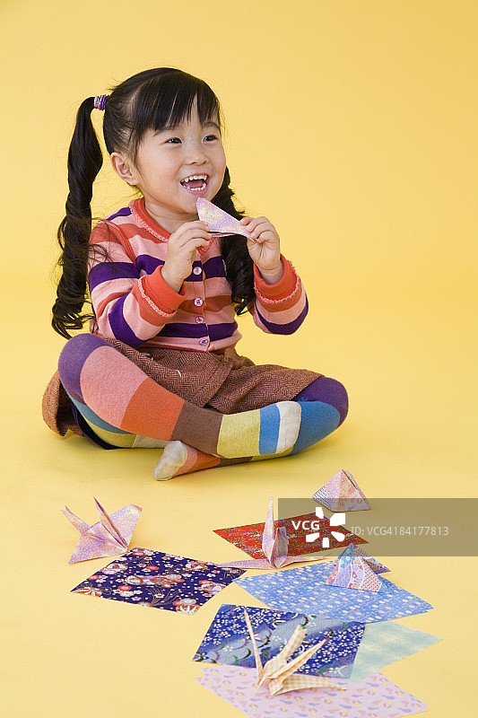 一个女孩在享受折纸的乐趣。图片素材