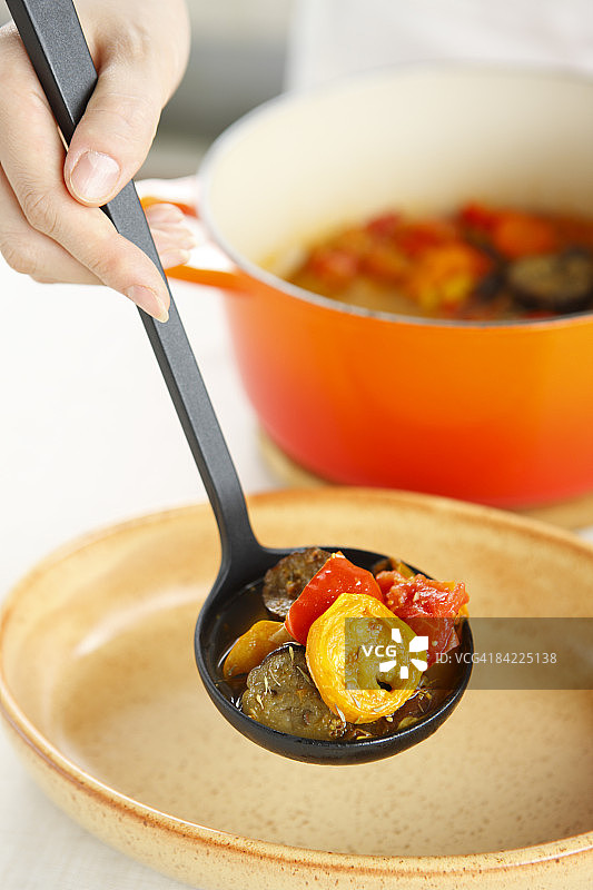 女人用勺子在盘子里炖菜，特写图片素材
