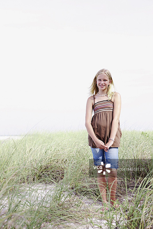 女孩站在长满草的沙丘上图片素材