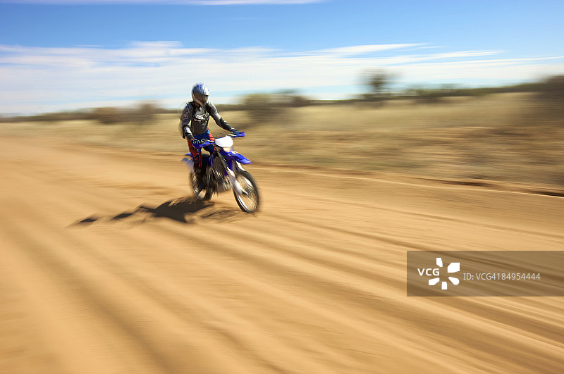 骑摩托车的人在土路上行驶，卡拉哈里沙漠中部，博茨瓦纳图片素材