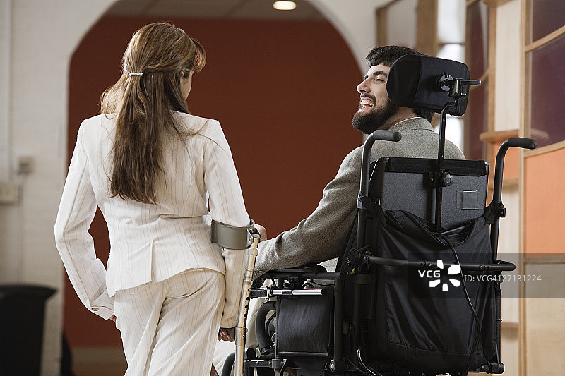 一个残疾男人和女人聊天的后视图。图片素材