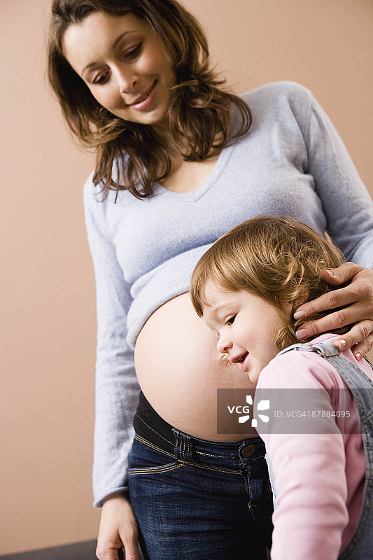女孩听着孕妇的肚子图片素材