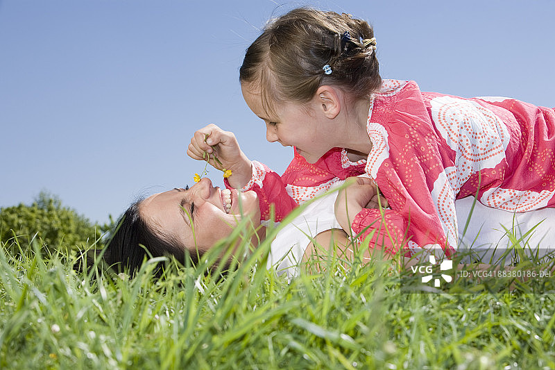 母亲和女儿(6-7)在草地上玩耍，特写图片素材