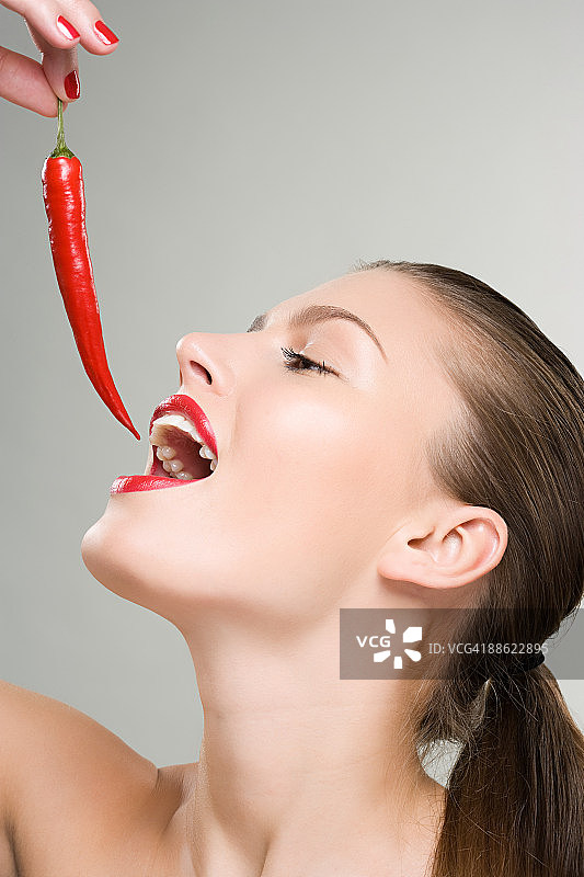一个女人把红辣椒拿在嘴边图片素材