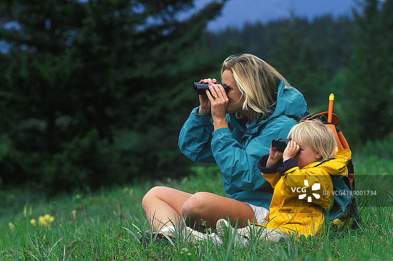 母亲和女儿通过望远镜在草地上看图片素材