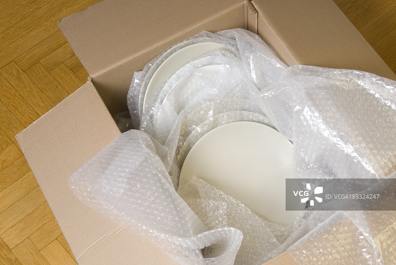 用气泡纸包裹的白色盘子堆放在一个移动的盒子里图片素材