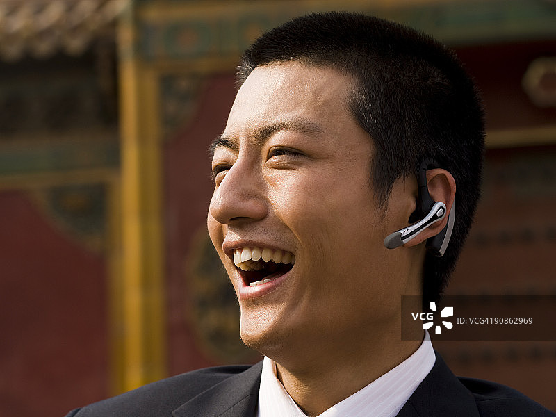 商人戴着耳机在户外微笑图片素材