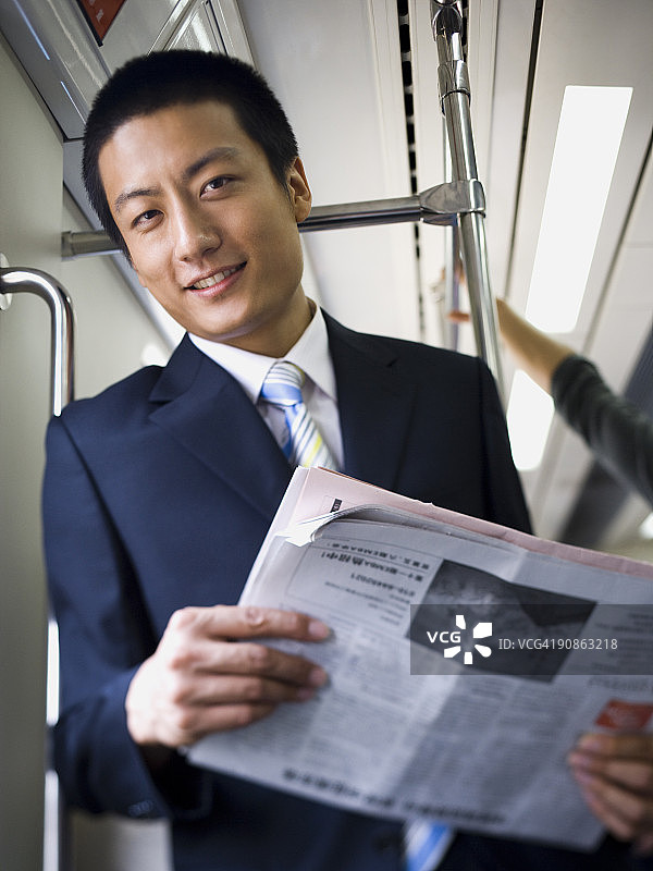 商人在地铁或公交车上带着报纸微笑图片素材