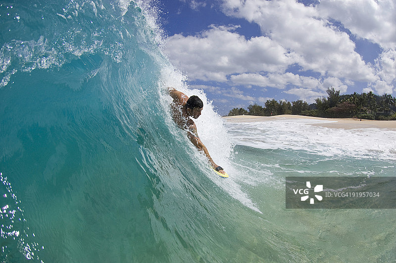 一个年轻人在夏威夷瓦胡岛北岸的Keiki海滩冲浪。图片素材