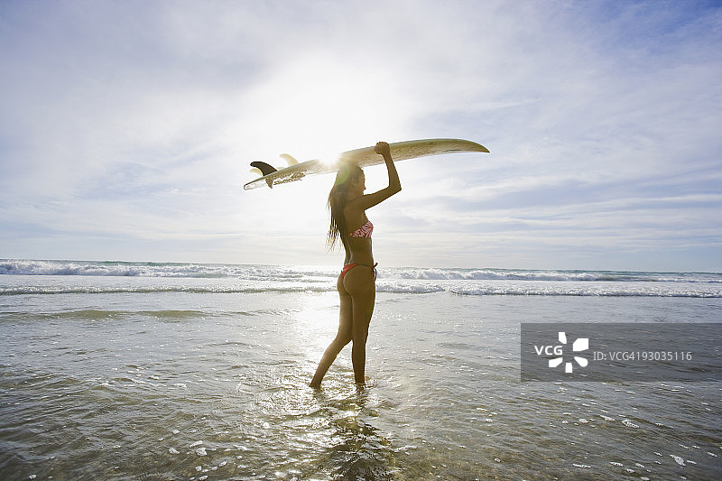 墨西哥下加利福尼亚卡波圣卢卡斯海滩上，一名妇女背着冲浪板图片素材
