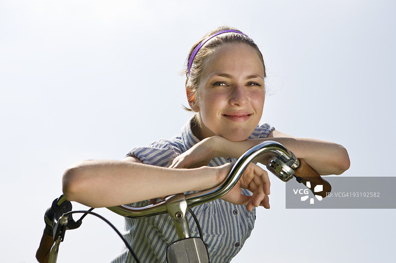 一个年轻女子斜靠在自行车把手上图片素材