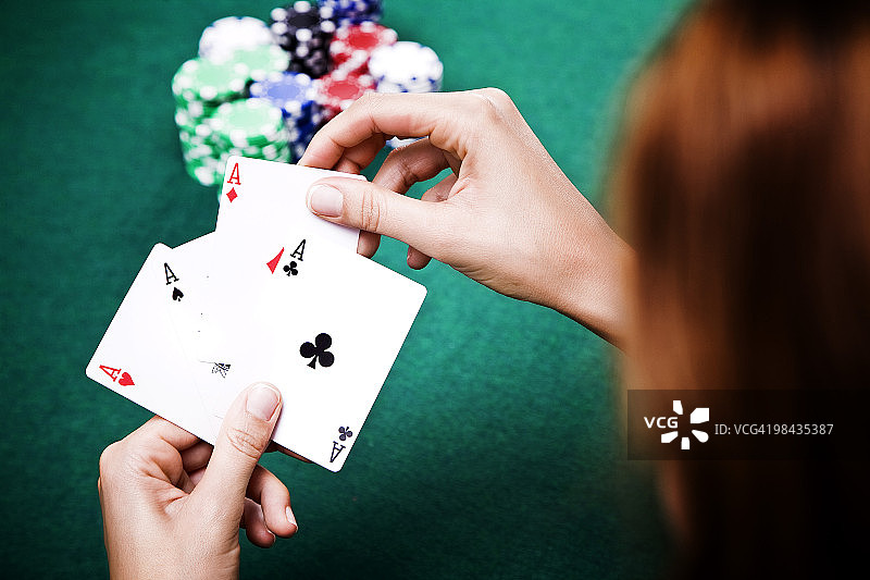 一个年轻女子在玩扑克，手里拿着三个ACES图片素材