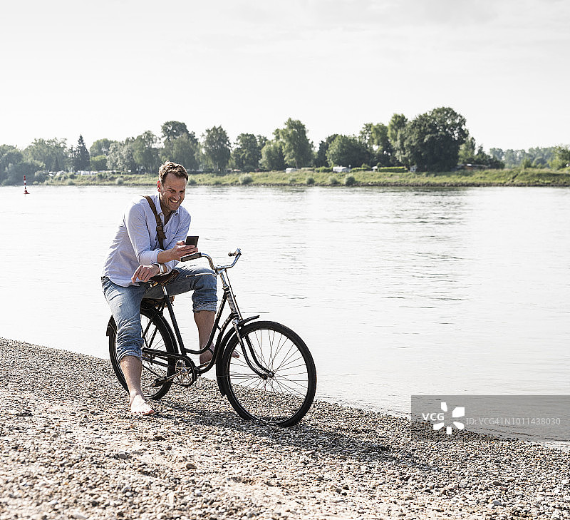 莱茵河岸边，一名骑着智能手机的成熟男子图片素材
