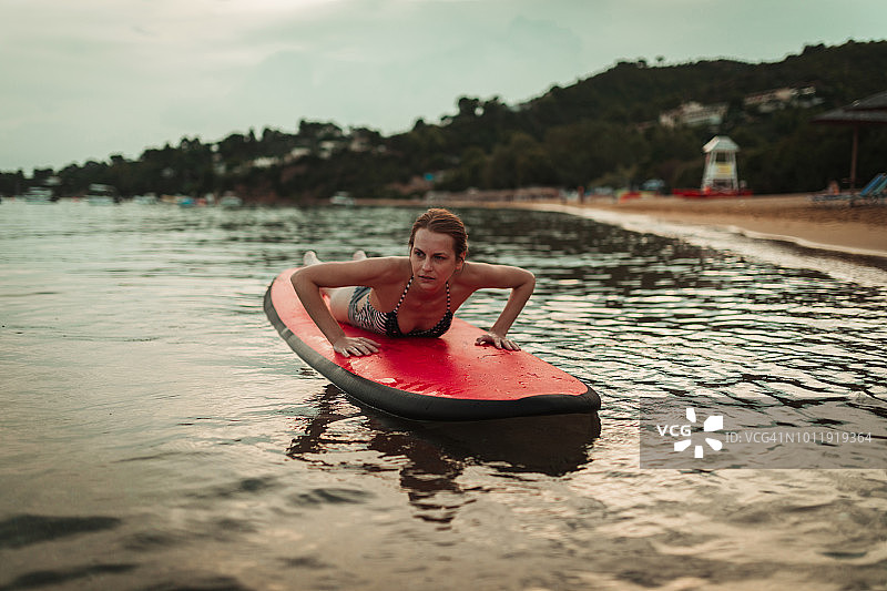 一个可爱的夏日，年轻女子在冲浪板上放松图片素材