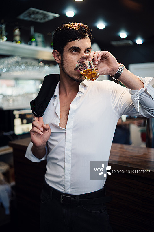 在酒吧里喝威士忌的绅士图片素材