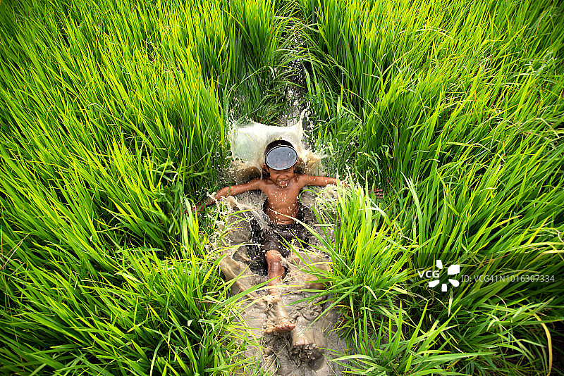 亚洲农民的孩子在农村的稻田里玩水，是美丽而又美丽的大自然带着微笑和幸福。图片素材