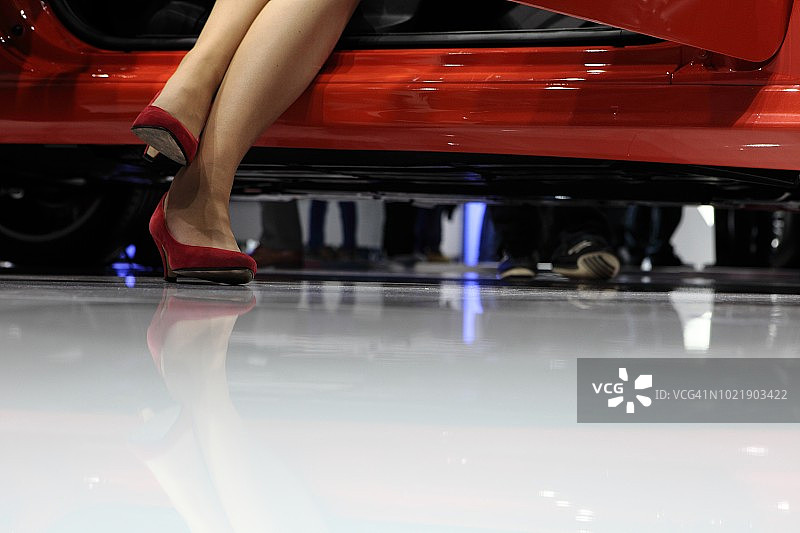 低角度的女人坐在车里穿着红色高跟鞋，腿只图片素材