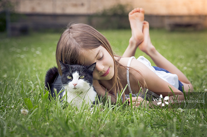 小女孩在草地上抱着一只猫图片素材