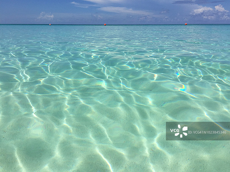 清澈的海水，底部是沙子，上面是蓝色的天空图片素材